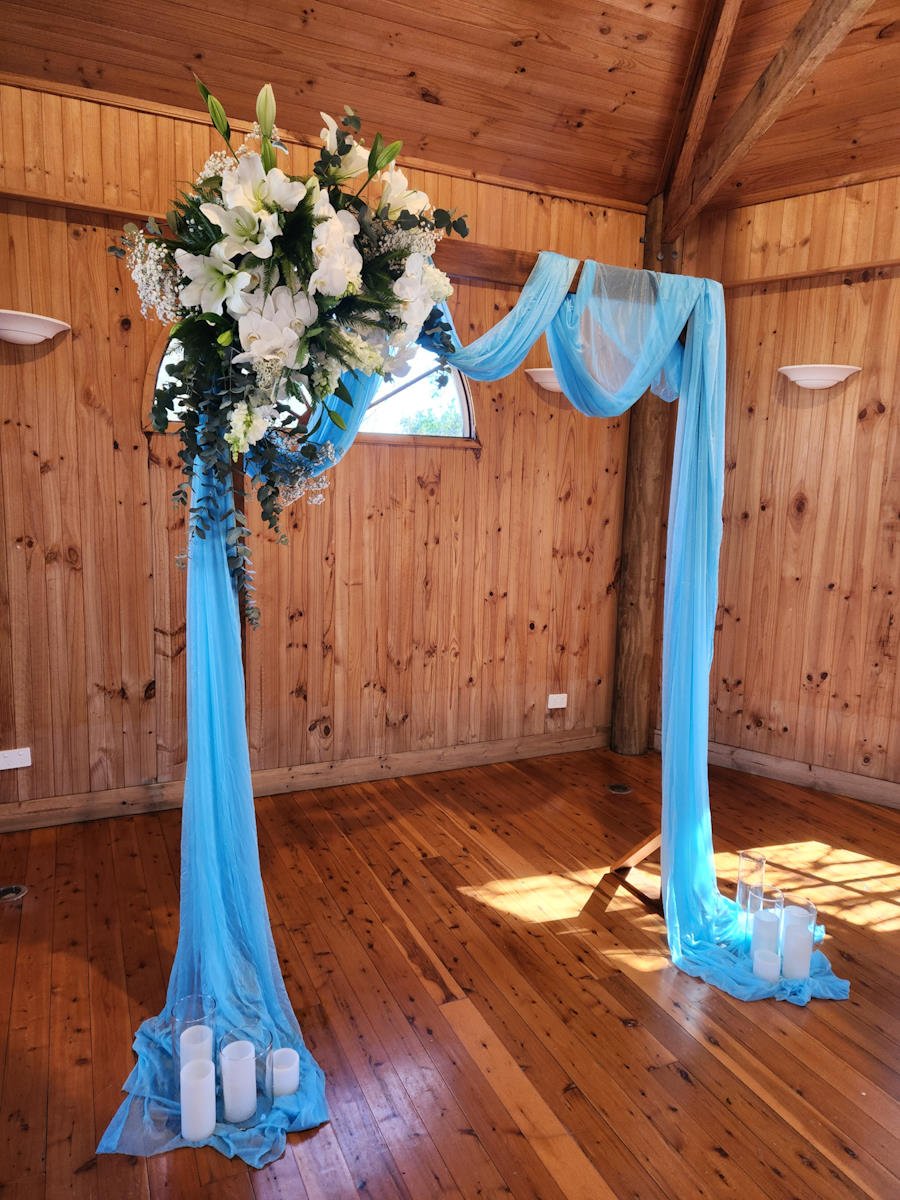 Timber Arch with flowers blue drapes and candles