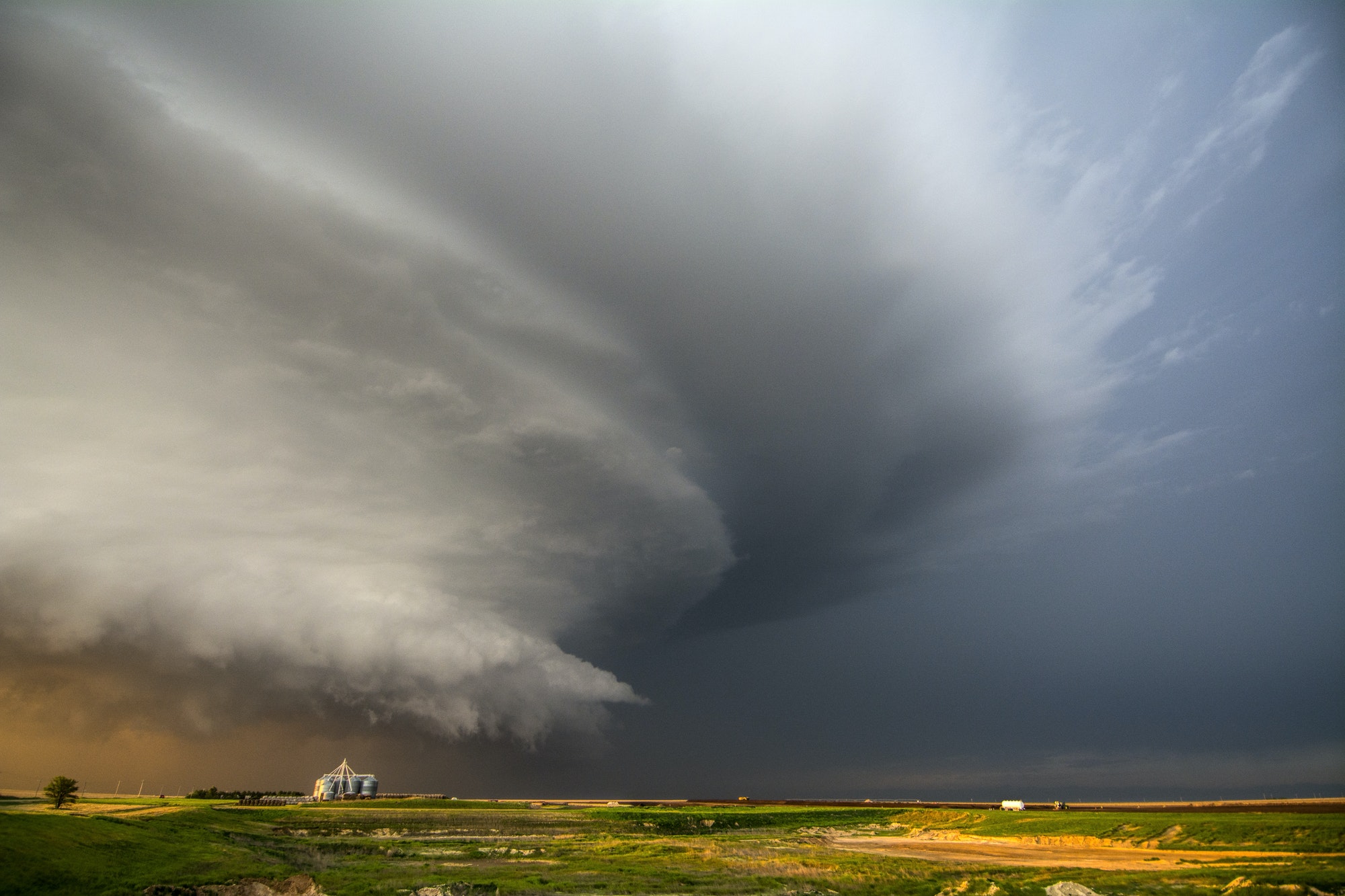 A tornado-producing supercell thunderstorm spinning over ranch land at sunset near Leoti, Kansas