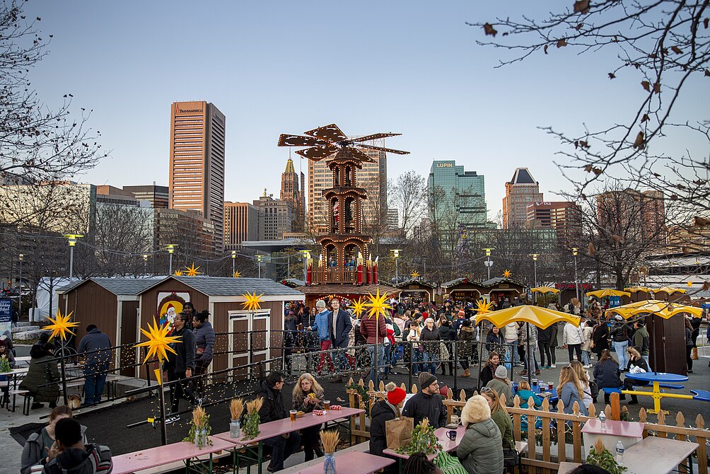 A group of people are sitting at tables at an outdoor market in Federal Hill, Baltimore.