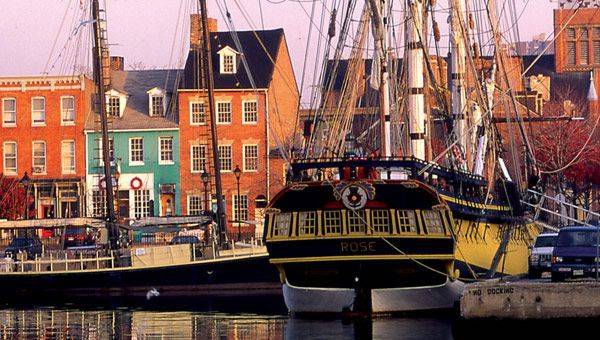 A boat docked in a harbor with buildings in the background.