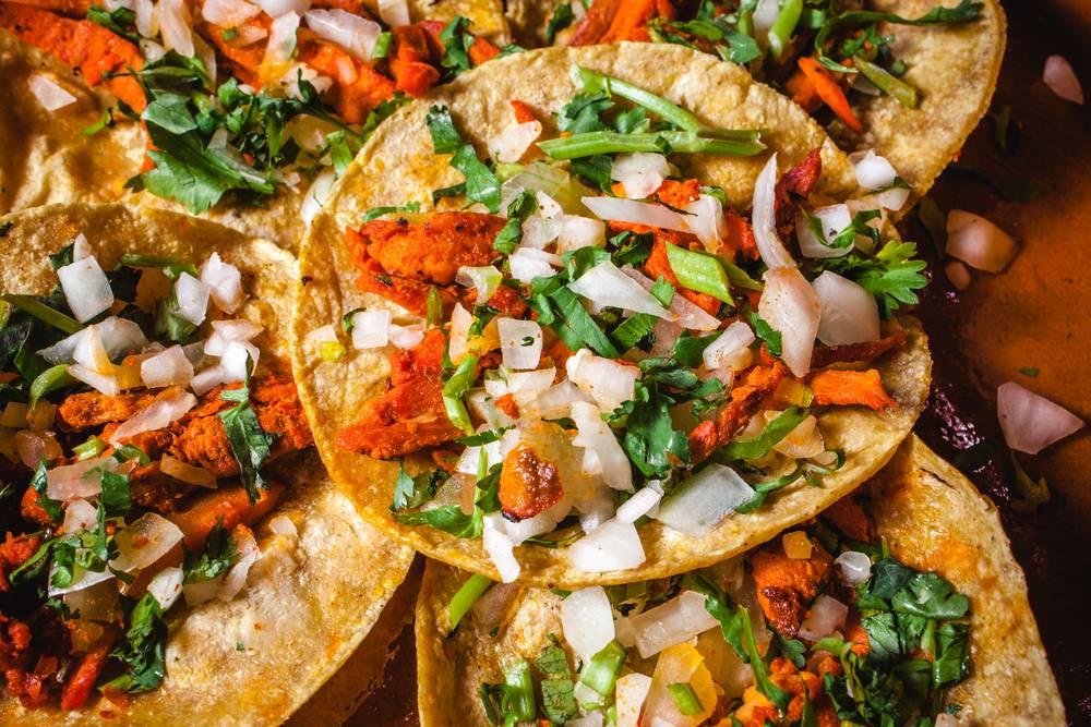 A plate of mexican tacos with onions and cilantro.