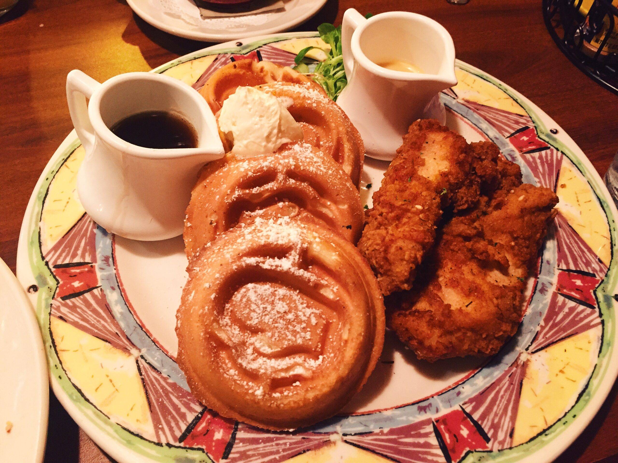 A plate of chicken and waffles on a wooden table.