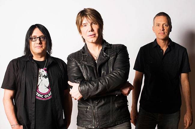 Three men posing for a picture in front of a white background.