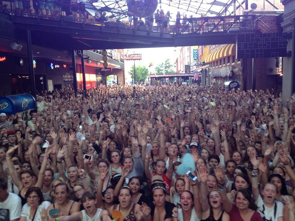 A crowd of people with their hands up in the air.