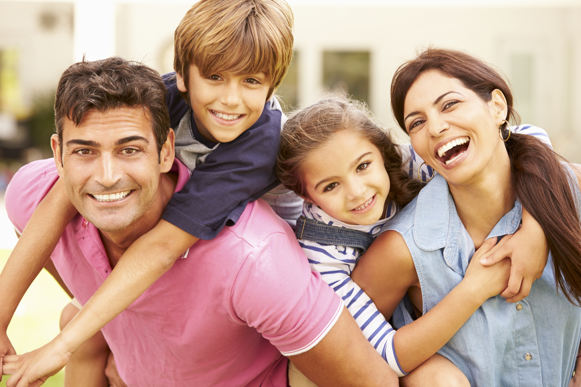 A family is happily holding a child on their shoulders.