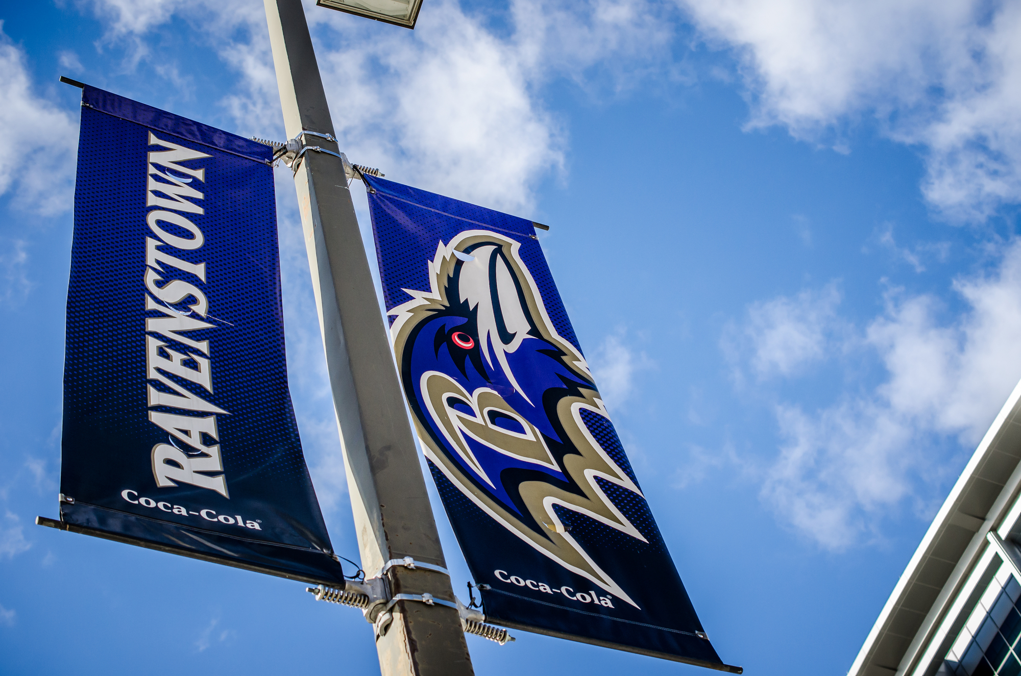 Two banners hanging from a pole in front of a building.