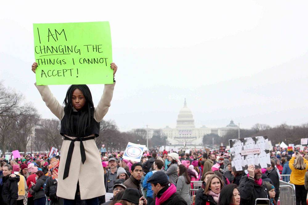 A woman holding up a sign that says i am changing the things i can't control.