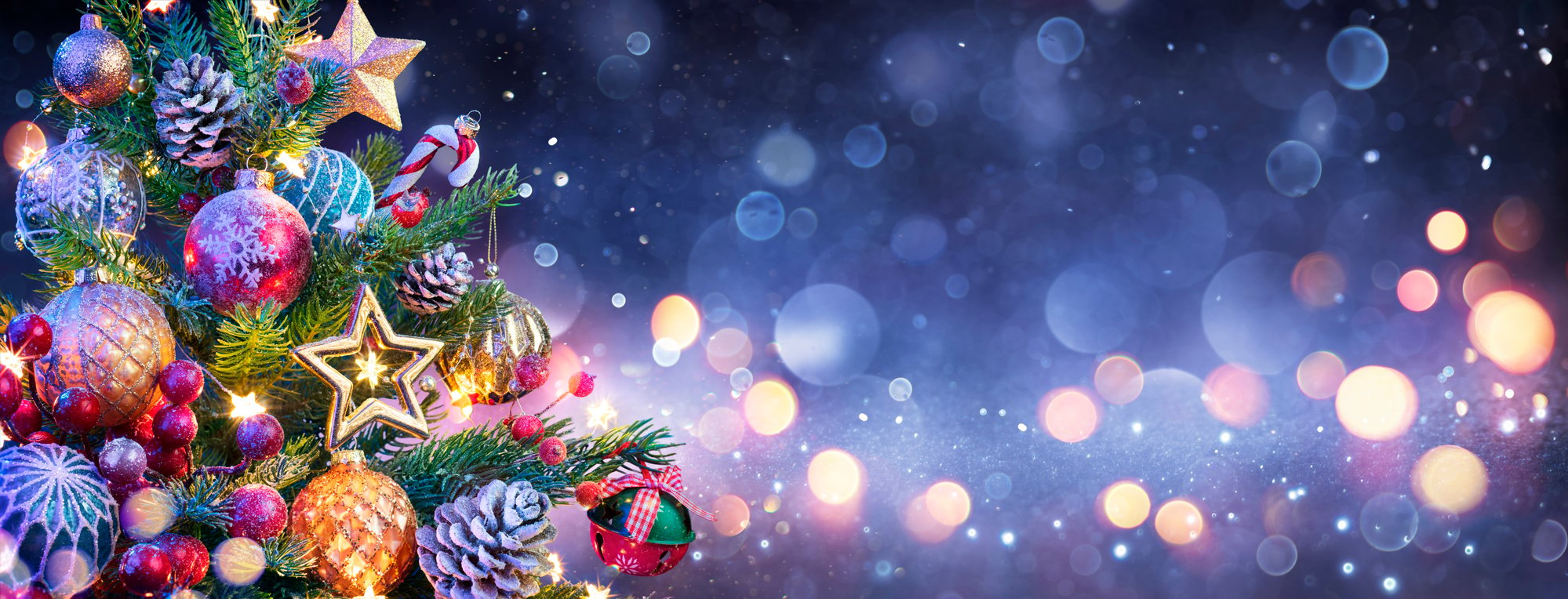 A Christmas tree adorned with colorful ornaments, set against a dark background at Power Plant Live.